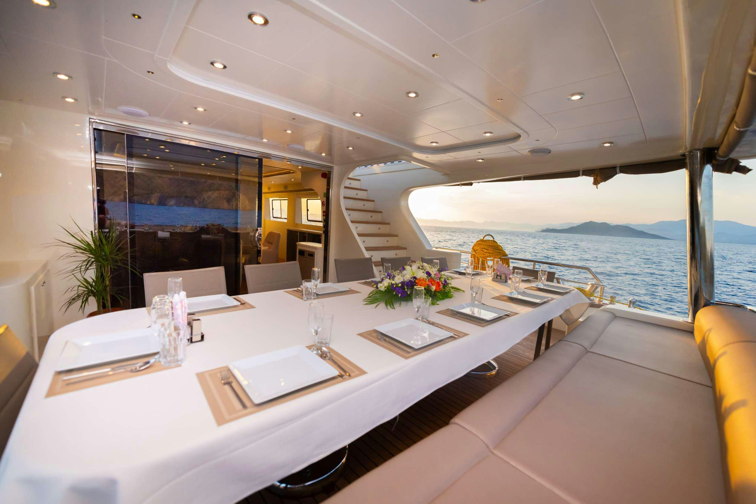a table with chairs and a view of the ocean aboard 88 YACHT Yacht for Charter