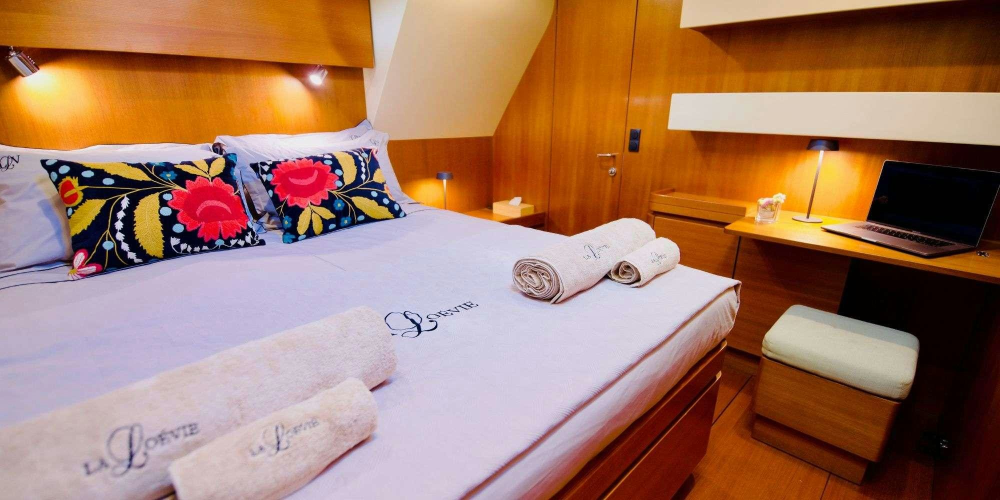 a bed with a white sheet and colorful pillows aboard LA LOEVIE Yacht for Charter