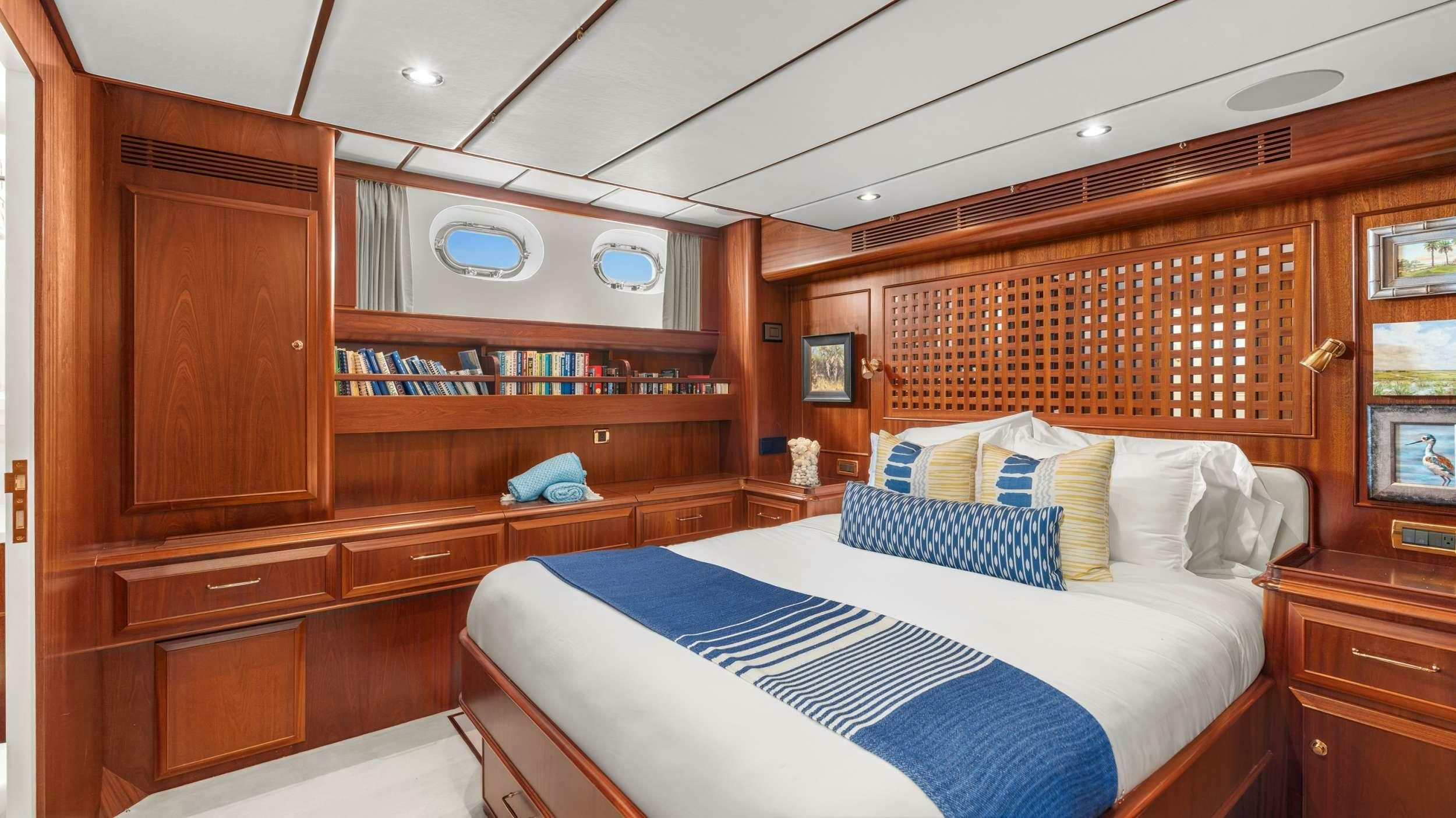 a bedroom with a bed and a bookcase aboard ABIDE Yacht for Charter