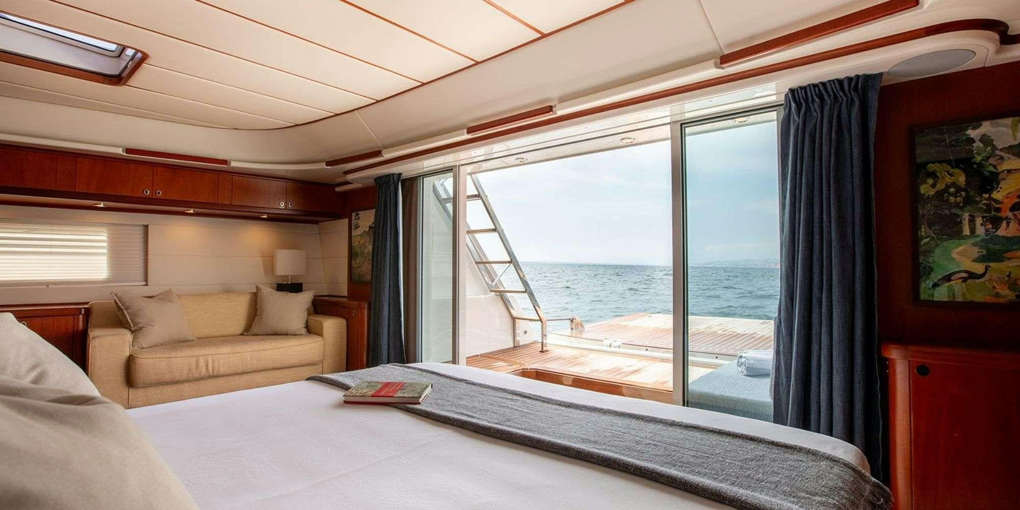 a bed and a couch in a room with a large window aboard SELENA Yacht for Charter