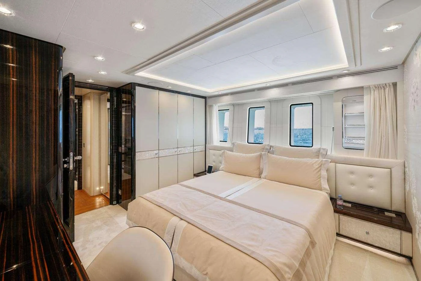 a bedroom with a bed and a curtained window aboard ALULIM Yacht for Charter