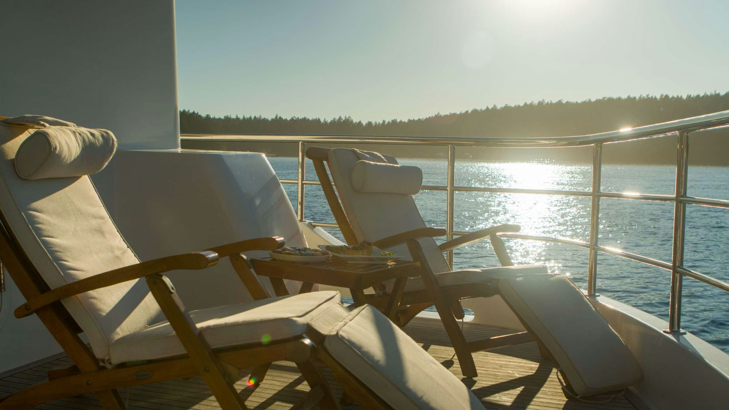a deck with chairs and a body of water in the background aboard SERENDIPITY Yacht for Charter