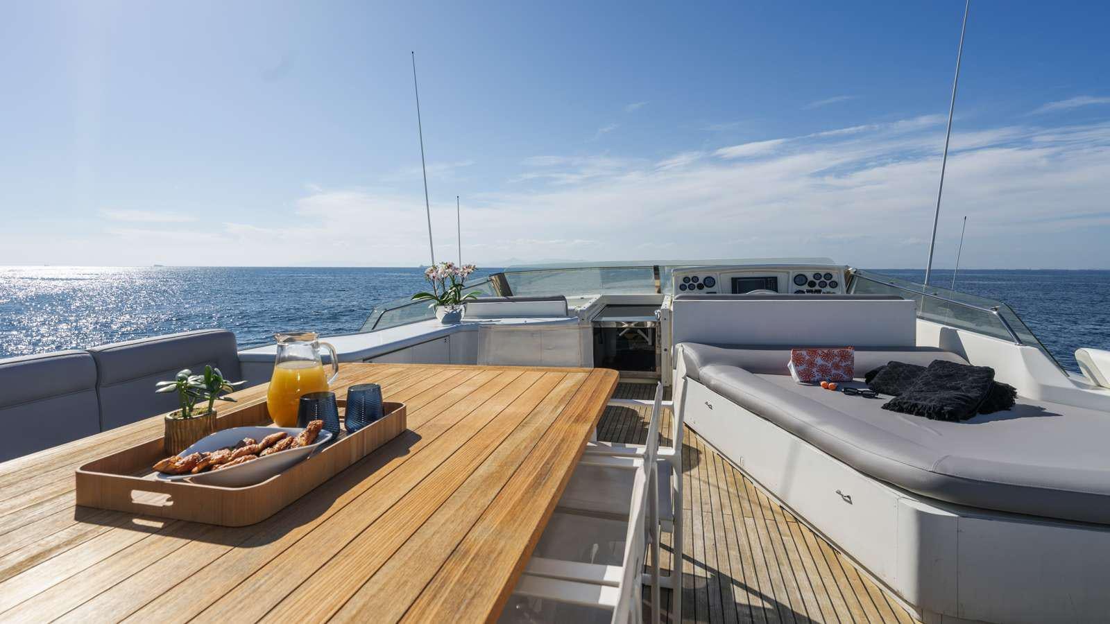 a table with food on it by a boat with a large body of water in the background aboard ALFA Yacht for Charter