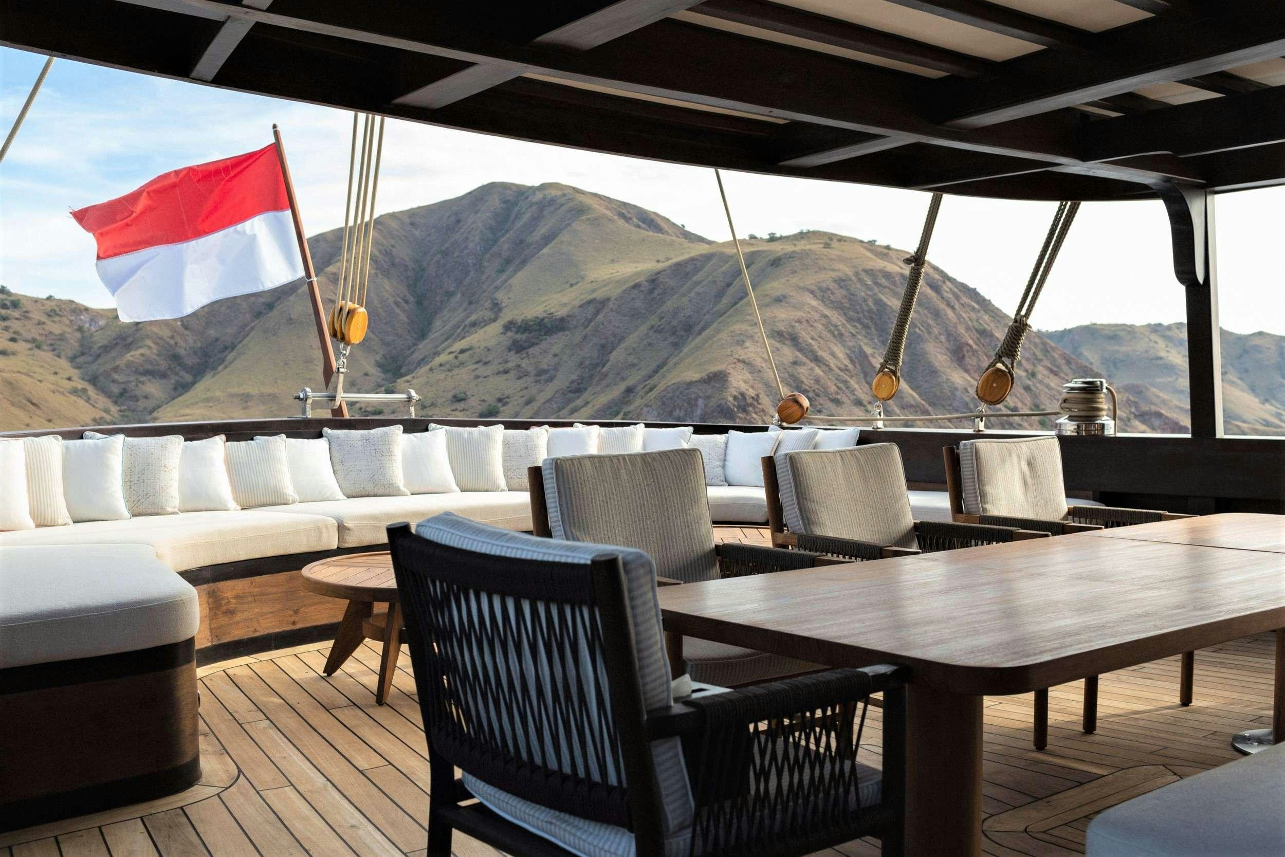 a deck with chairs and a flag aboard VELA Yacht for Charter