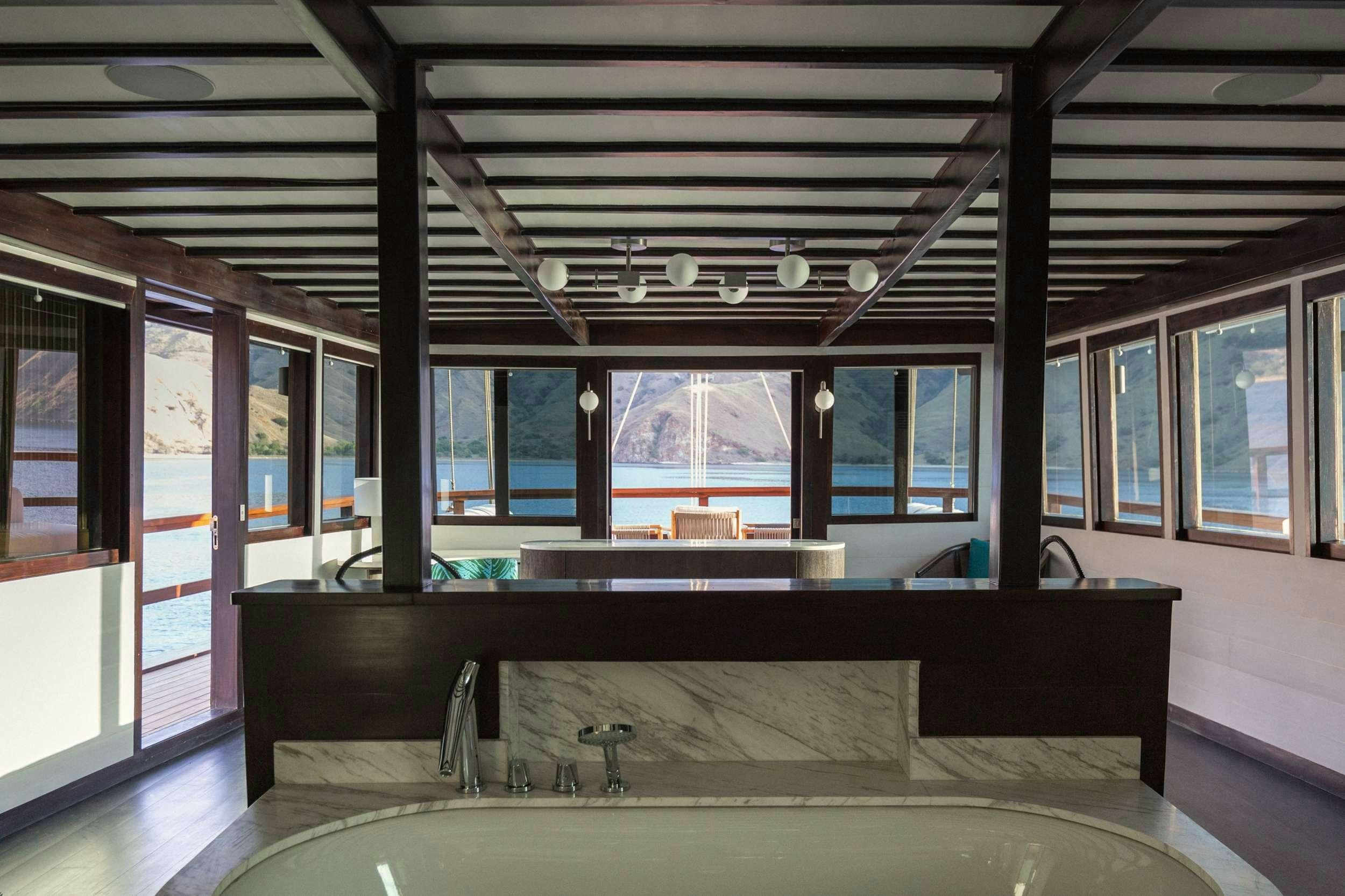 a room with a pool table and a large window aboard VELA Yacht for Charter