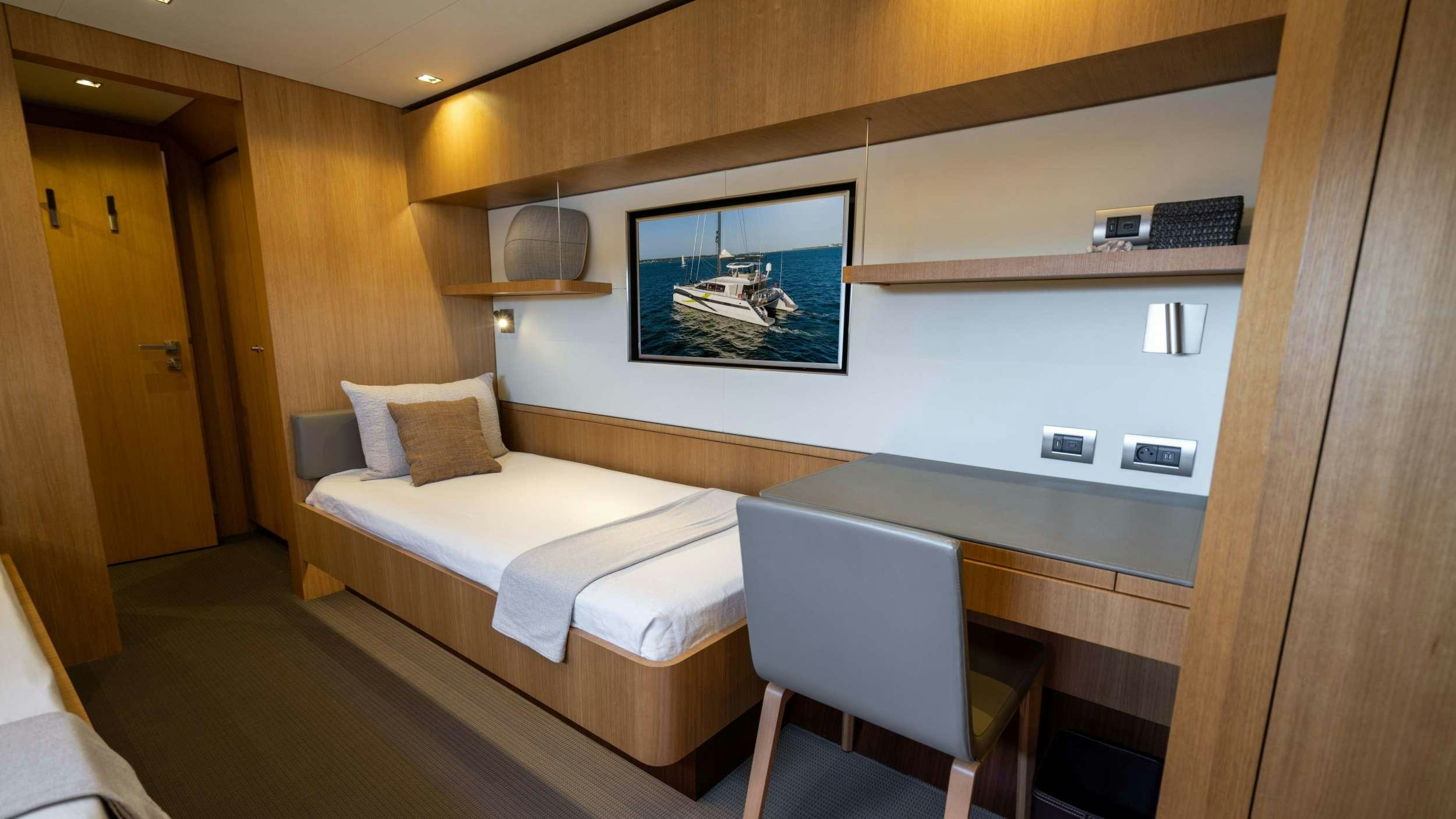 a room with a bed and a television on the wall aboard NDS EVOLUTION Yacht for Charter