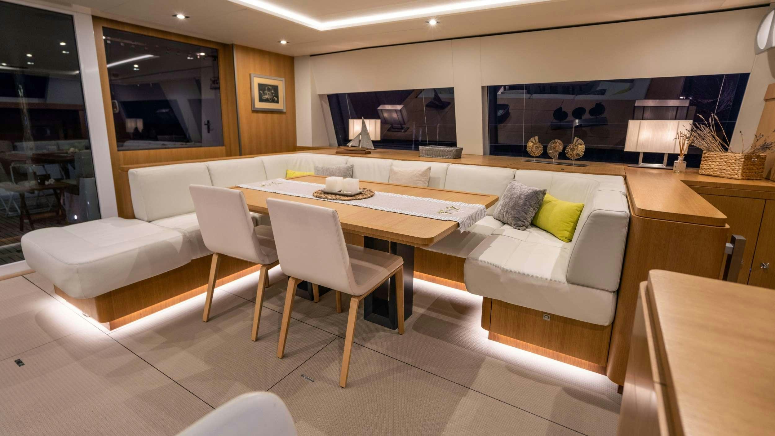 a room with a table chairs and a couch aboard NDS EVOLUTION Yacht for Charter