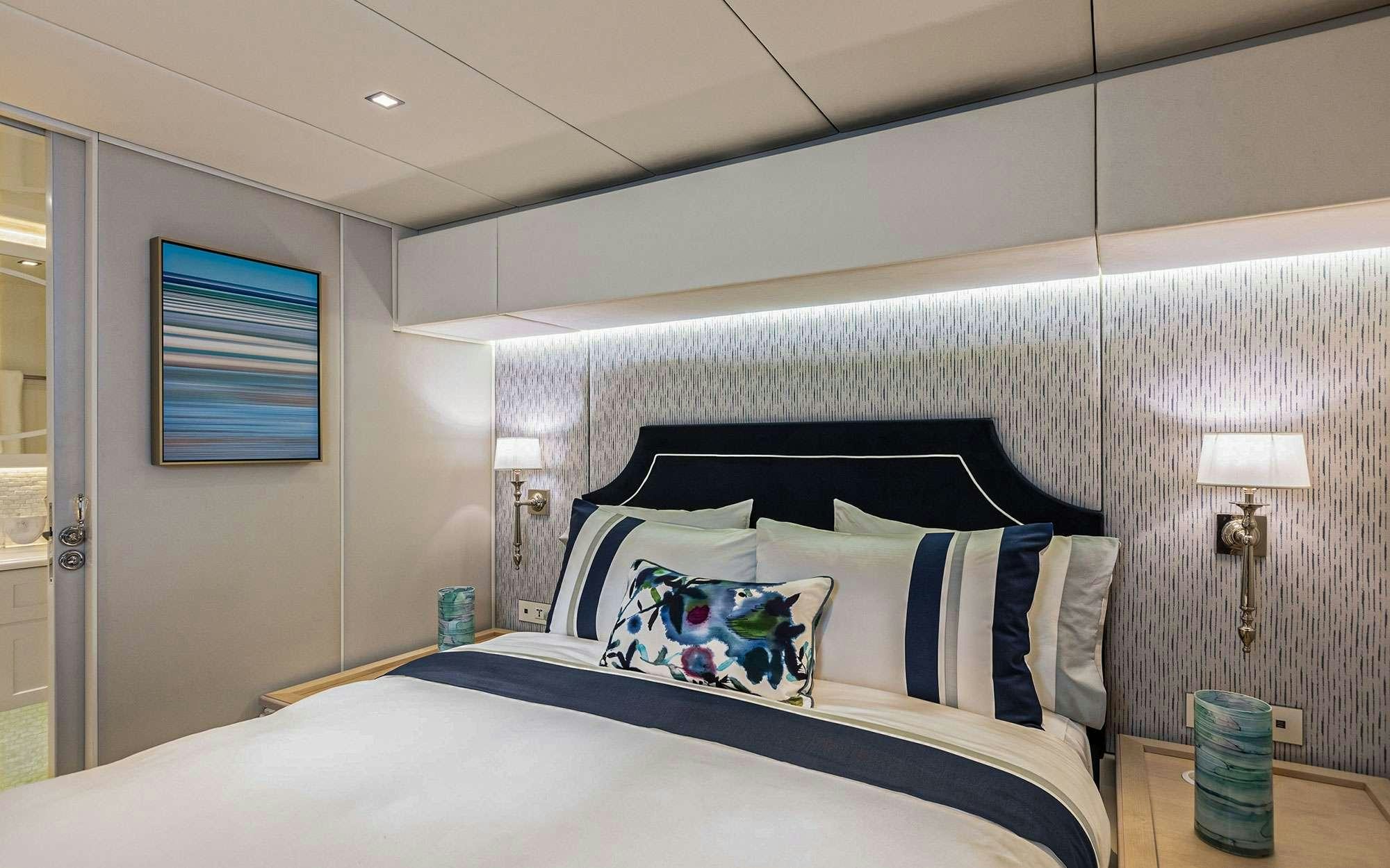 a bed with blue and white sheets aboard BUNDALONG Yacht for Charter