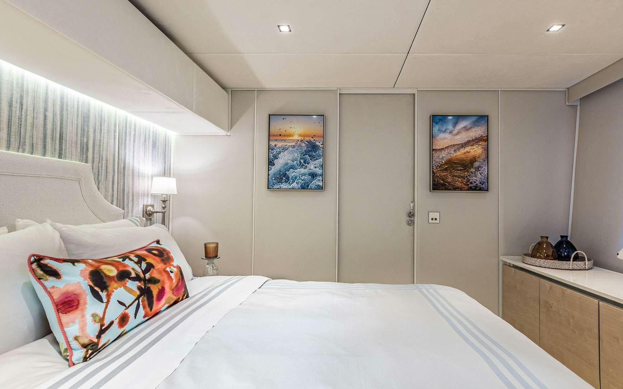 a bedroom with a bed and a painting on the wall aboard BUNDALONG Yacht for Charter