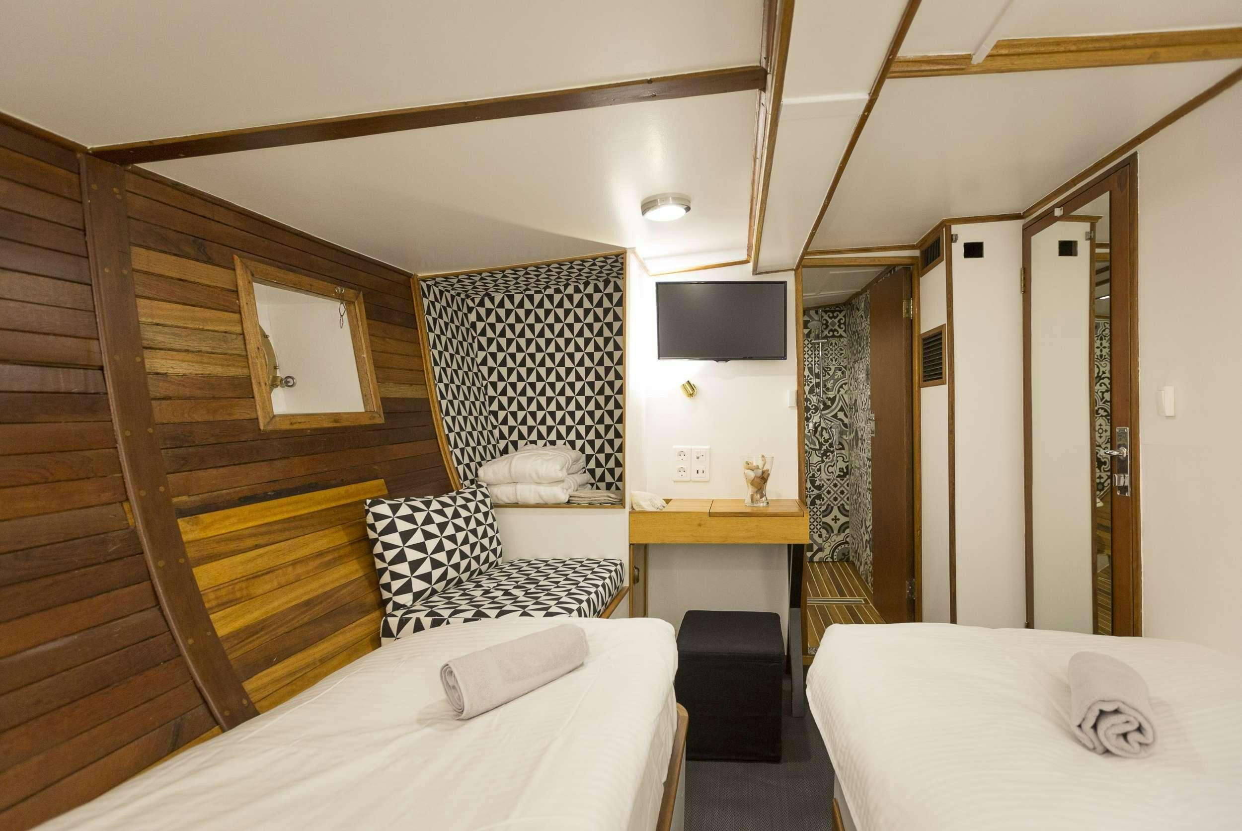 a bedroom with a bed and a desk aboard COSMOS Yacht for Charter