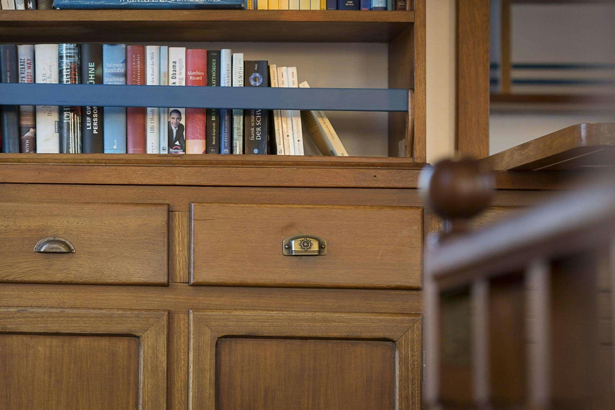 a wooden shelf with books aboard COSMOS Yacht for Charter