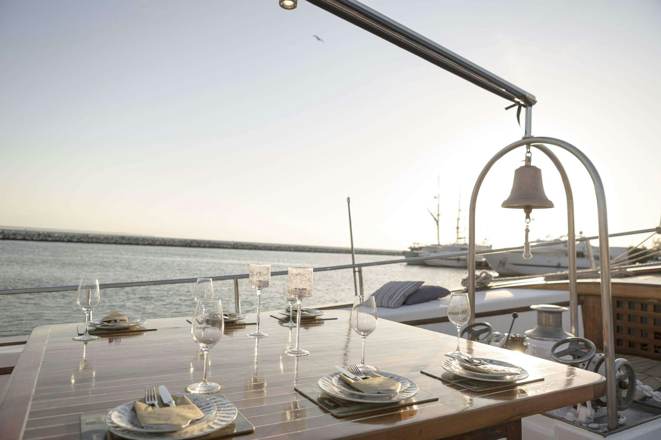 a table with wine glasses and a view of the ocean aboard COSMOS Yacht for Charter