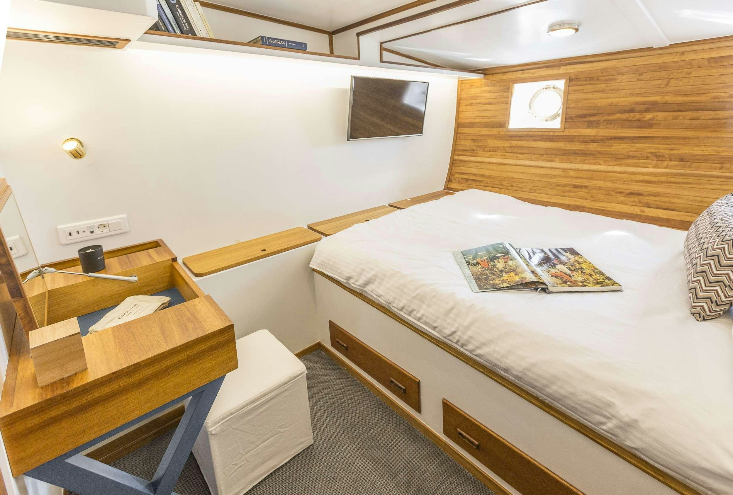 a room with a bed and a desk aboard COSMOS Yacht for Charter