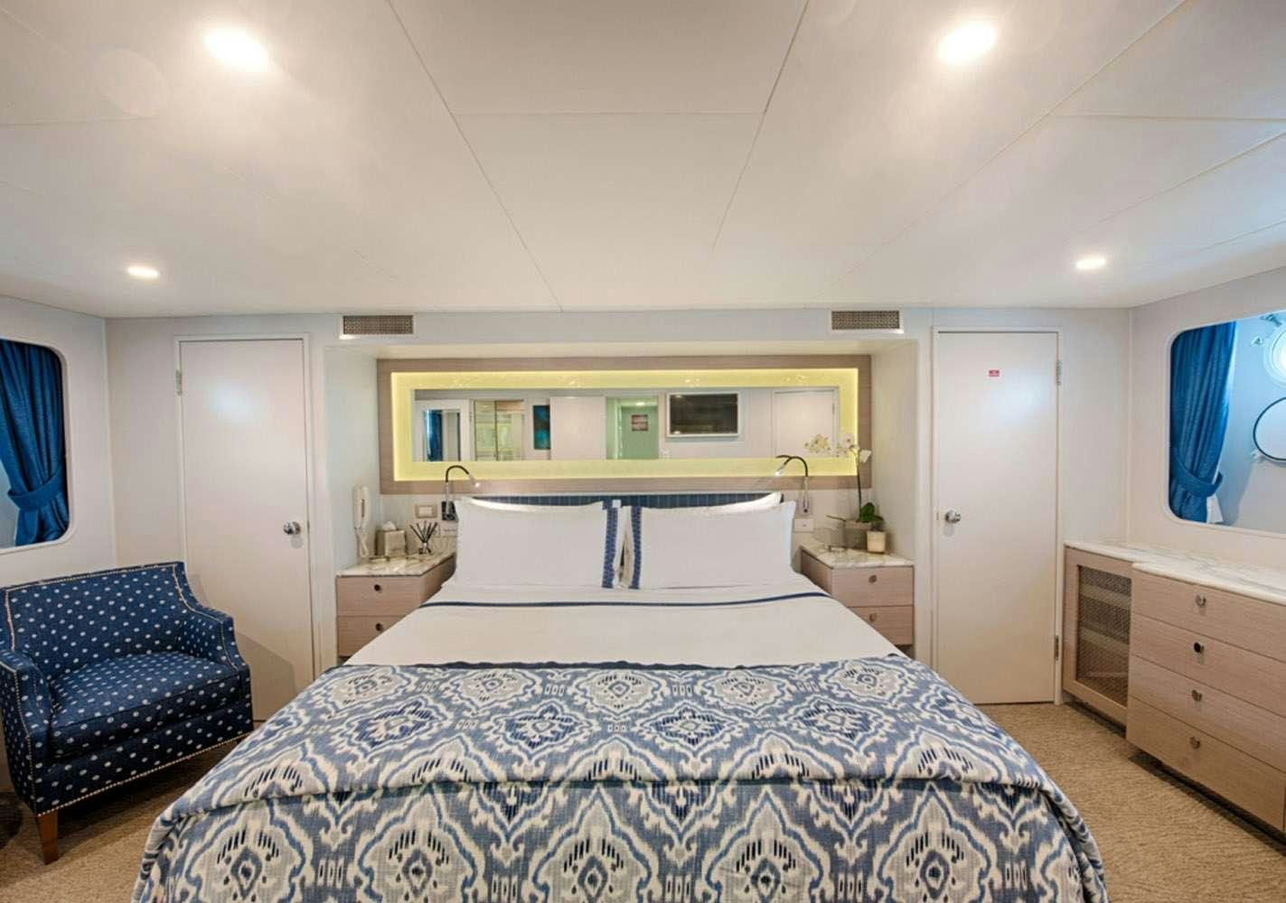 a bedroom with a bed and a chair aboard SHORETHING Yacht for Charter