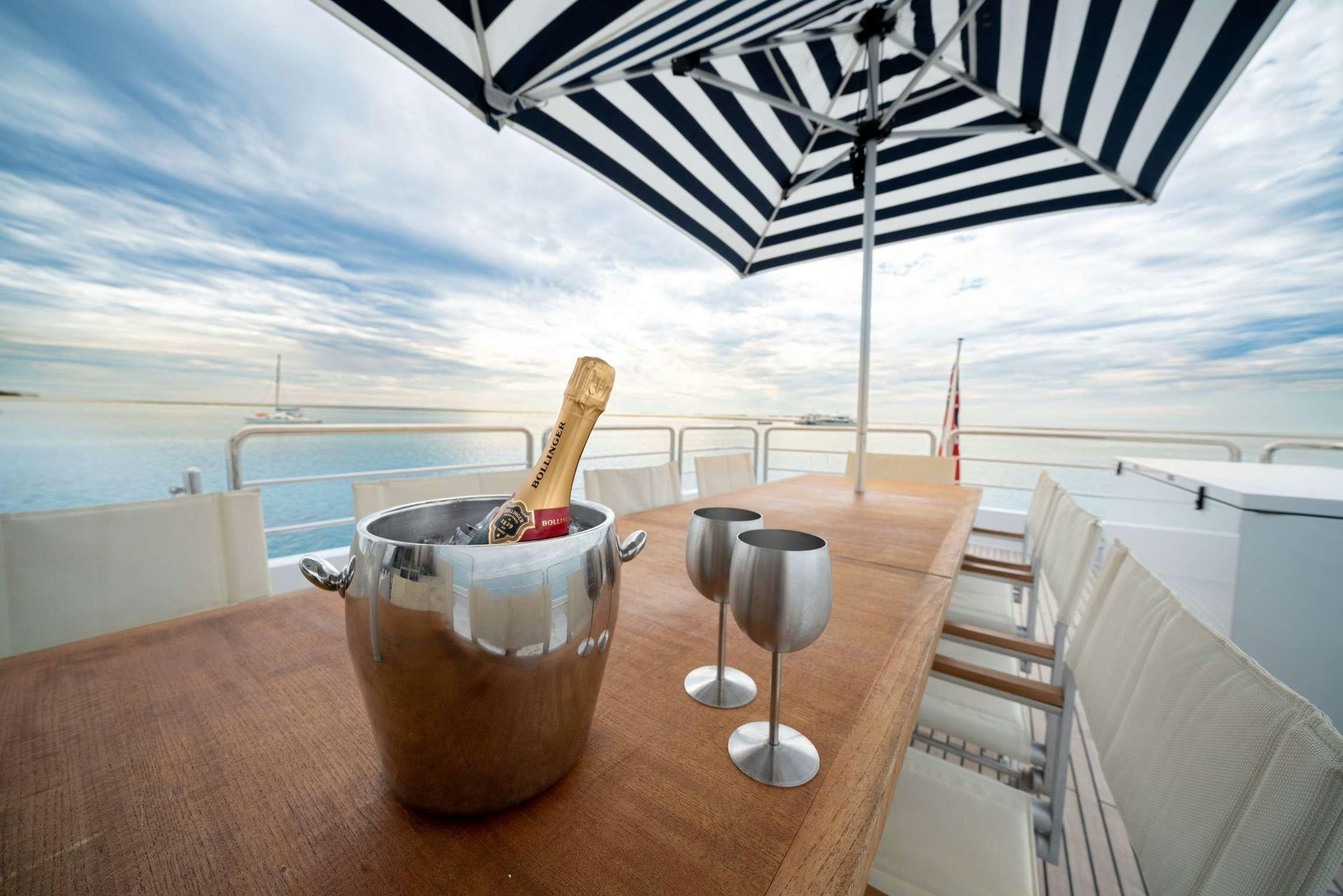 a glass of beer and a glass on a table with a beach view aboard SHORETHING Yacht for Charter