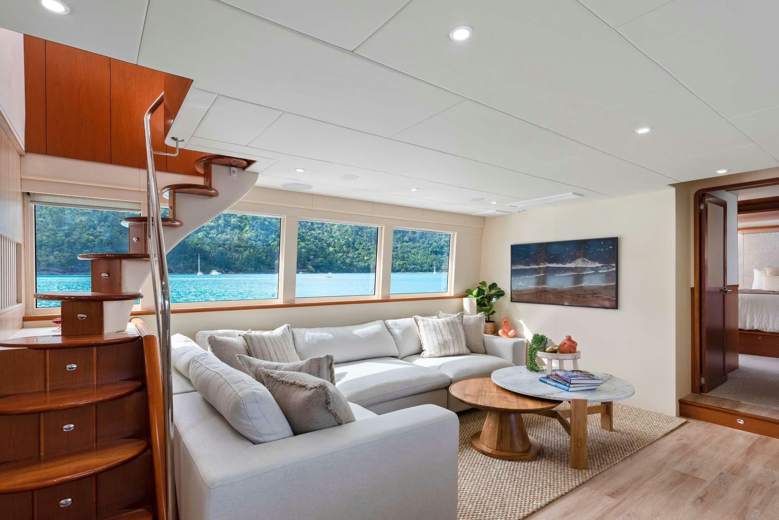 a living room with a white couch and a wood staircase aboard MATRIX III Yacht for Charter