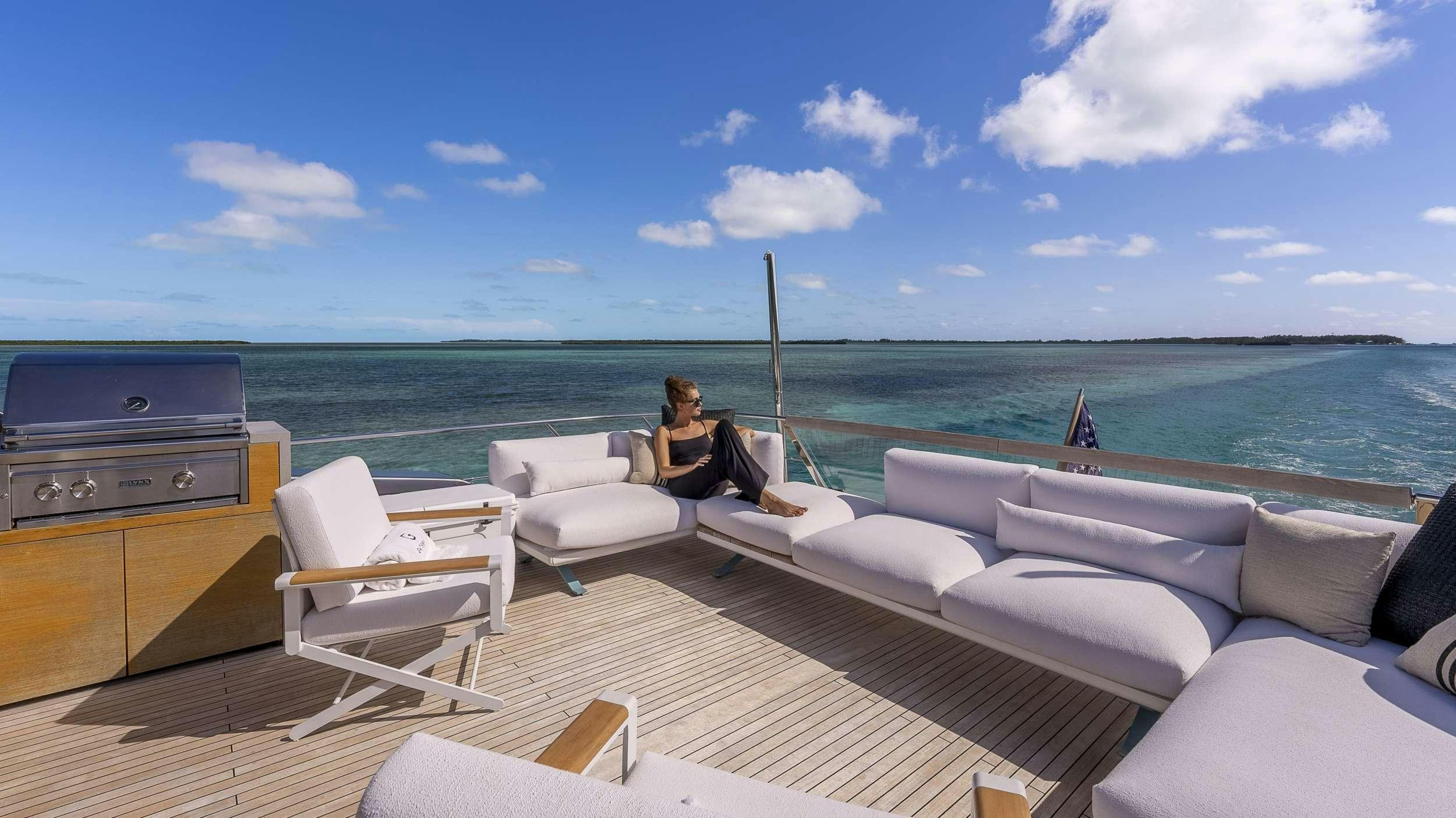 a person sitting on a couch on a deck overlooking the ocean aboard GATSBY Yacht for Charter