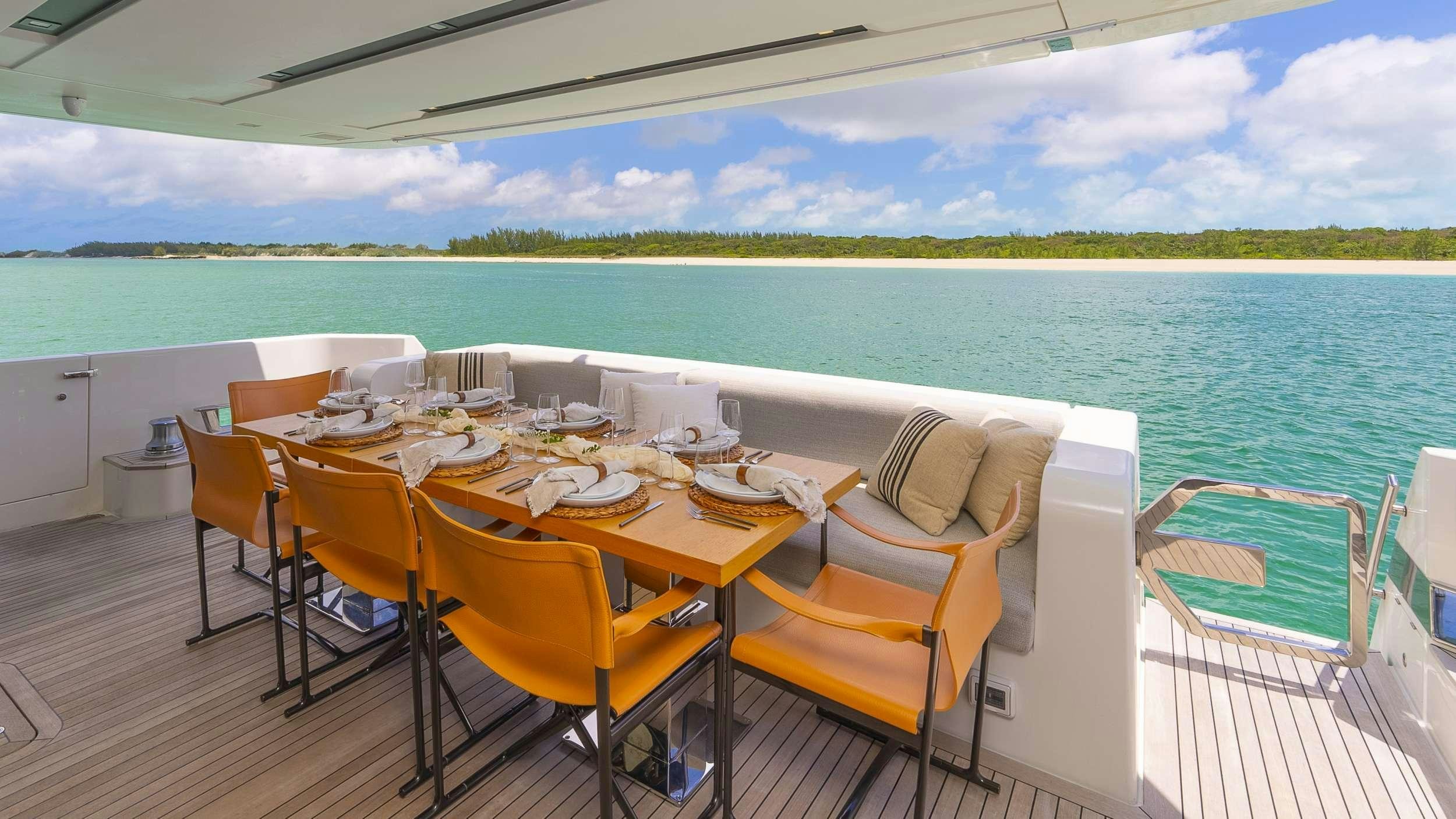 a table set for a meal on a balcony overlooking a beach aboard GATSBY Yacht for Charter