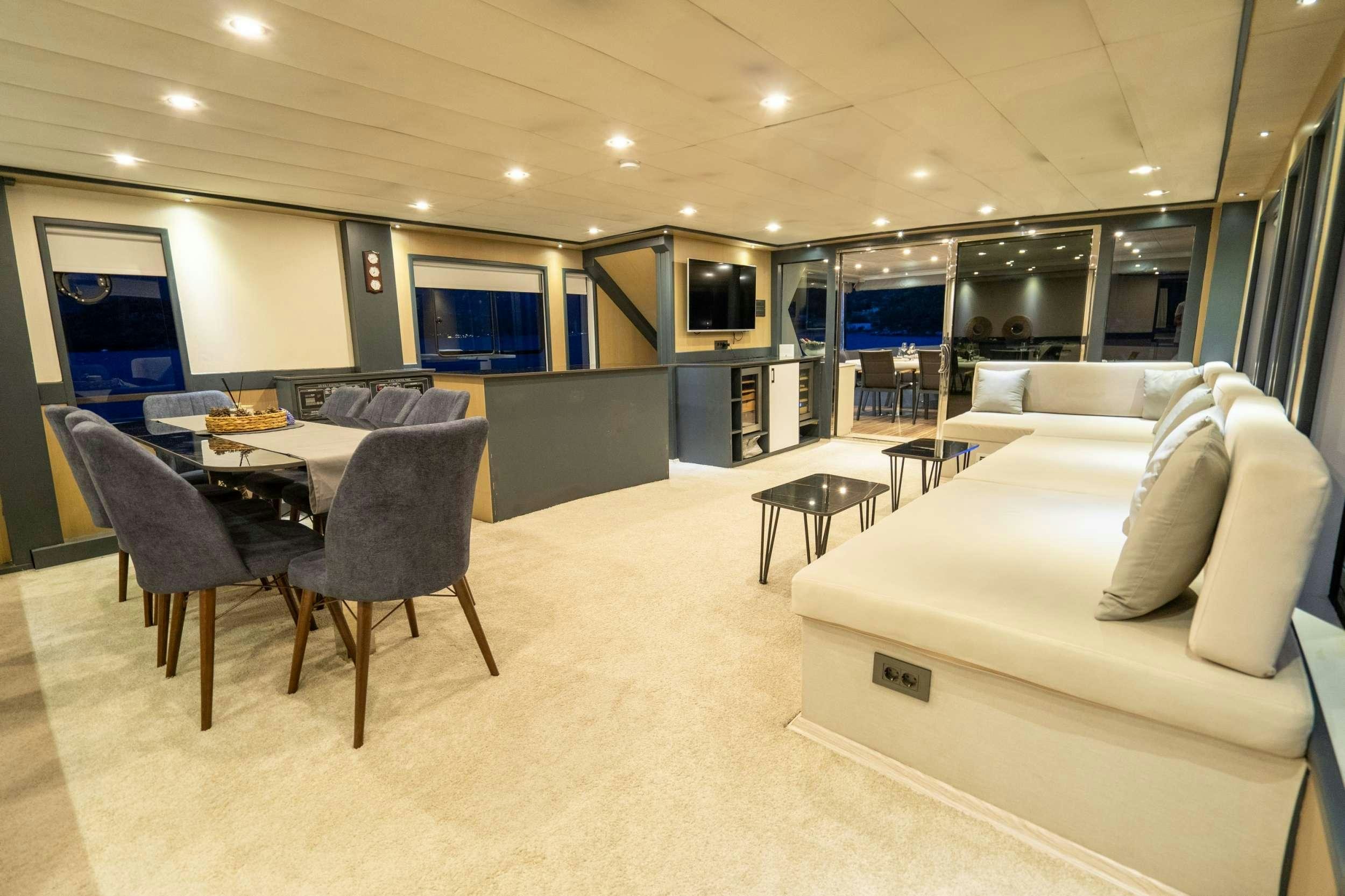 a large room with a couch and a table and chairs aboard IMPACT Yacht for Charter