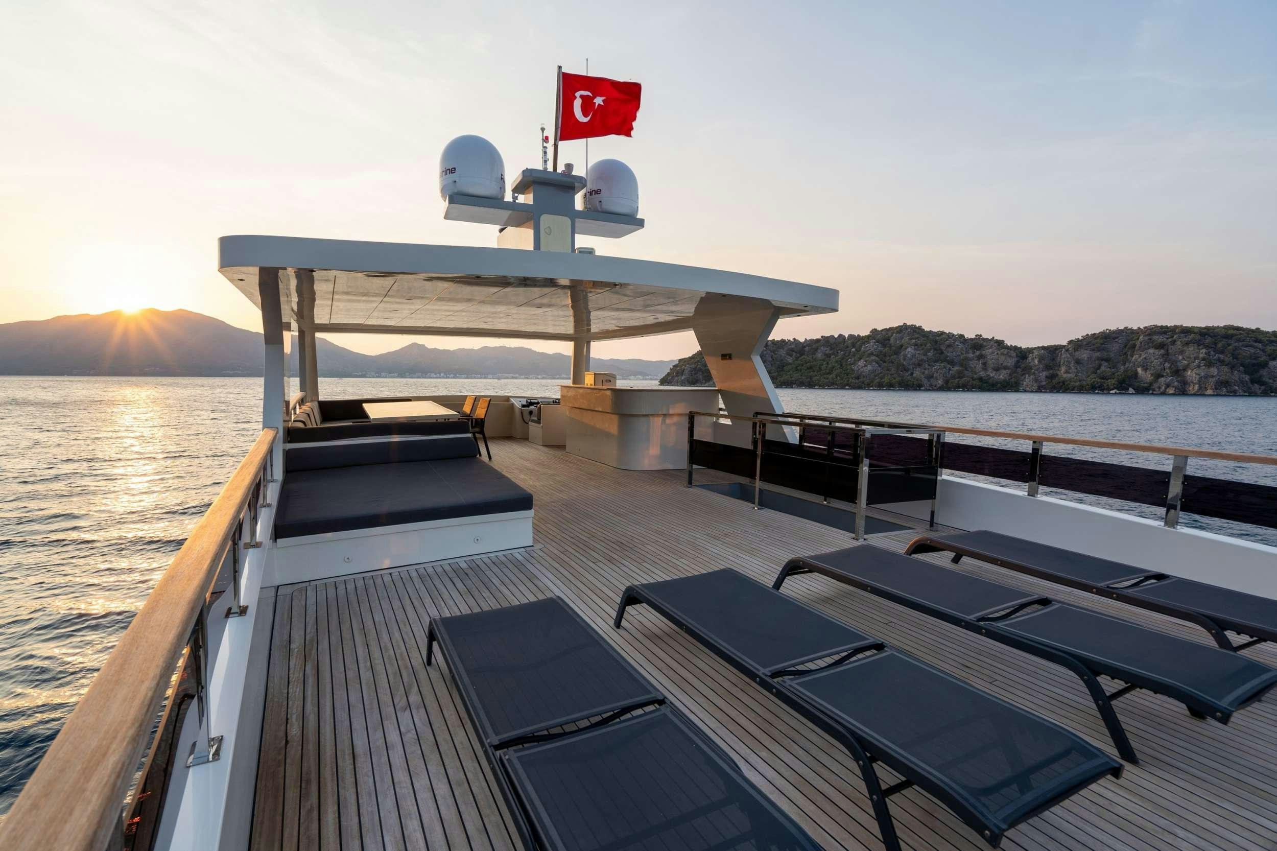 a deck with a large boat and a flag on it aboard IMPACT Yacht for Charter