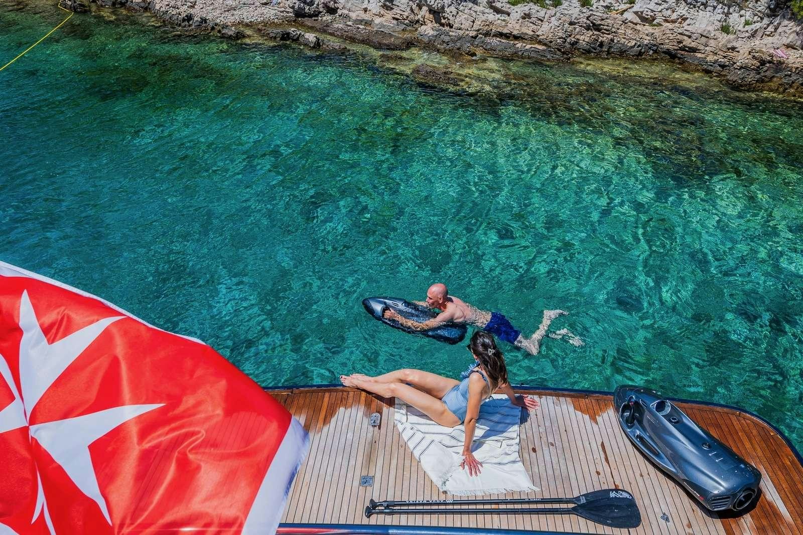 a couple of people lounging on a lounge chair on a beach aboard GITANA II Yacht for Charter