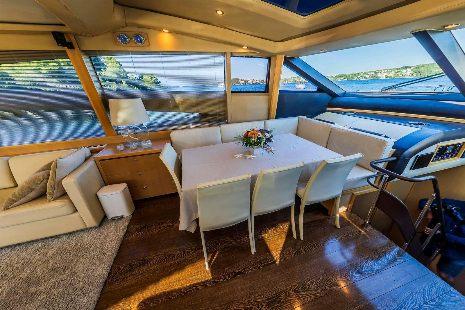 a dining table and chairs in a room with a large window aboard GITANA II Yacht for Charter