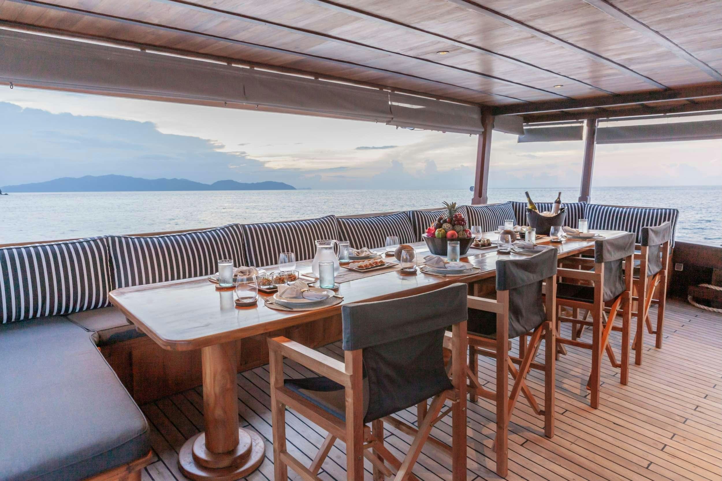 a table set for a meal on a deck overlooking the ocean aboard REBEL Yacht for Charter