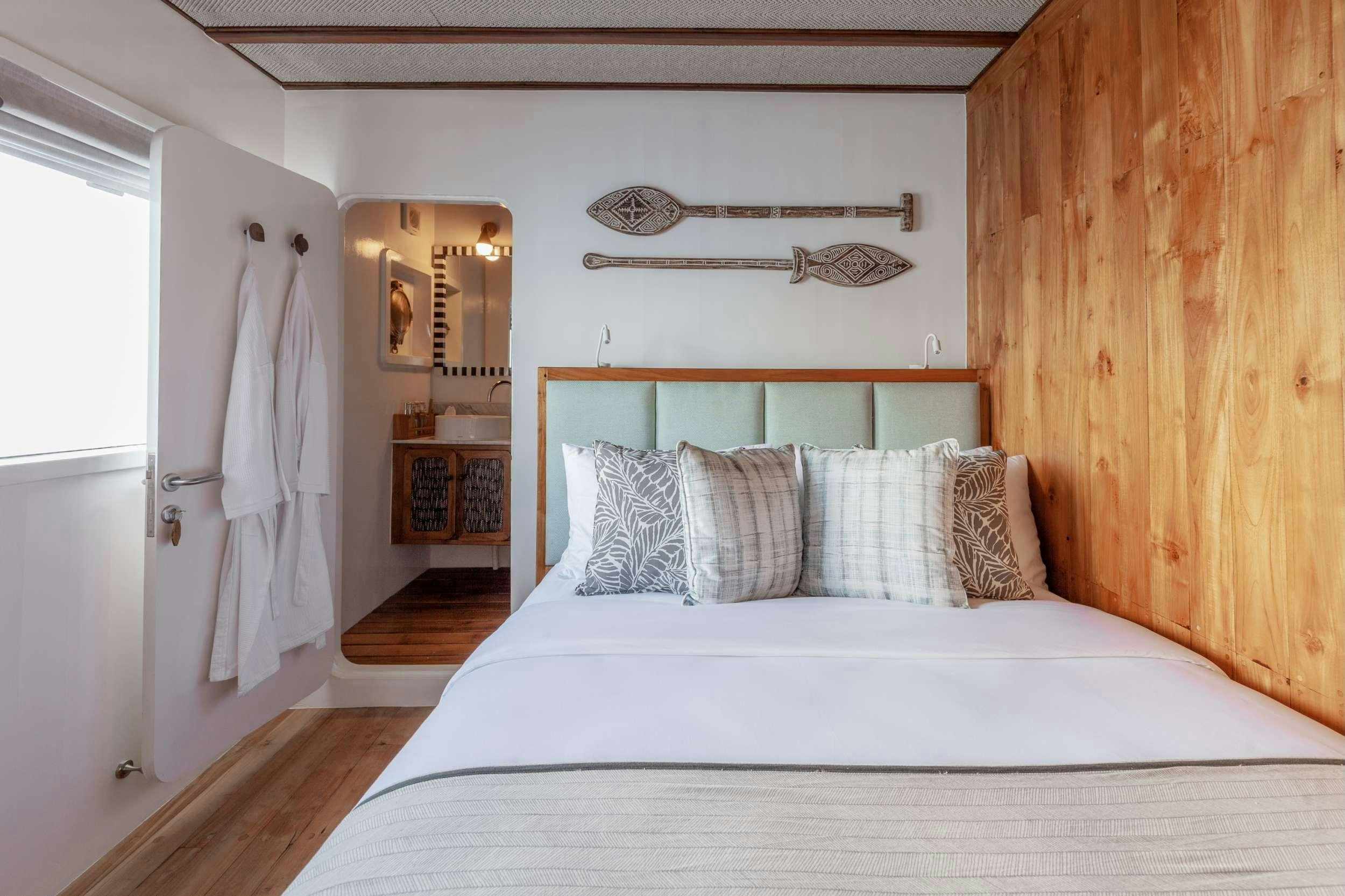 a bedroom with a bed and a wood wall aboard REBEL Yacht for Charter