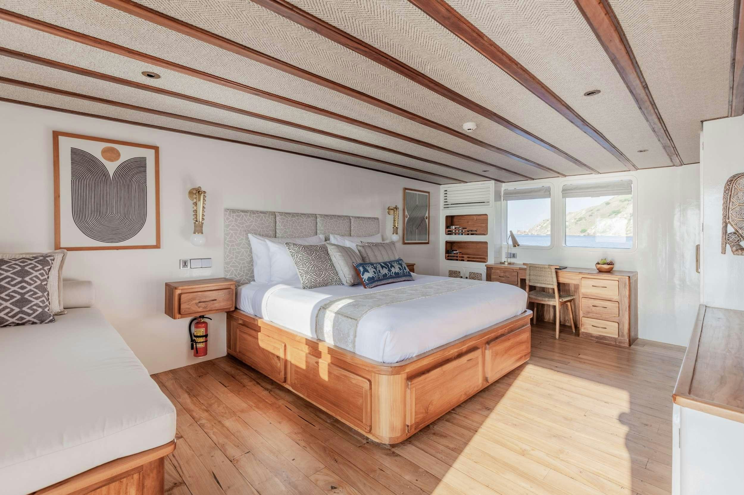 a bedroom with a bed and a desk aboard REBEL Yacht for Charter