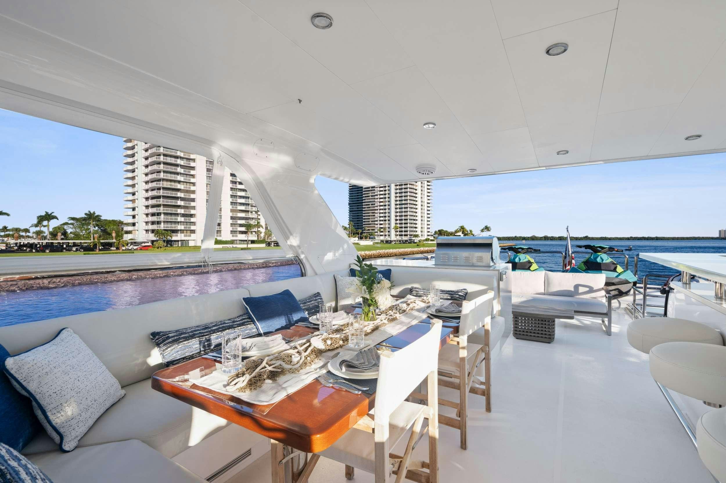 a table and chairs in a room with a large body of water in the background aboard PILOT LOUNGE Yacht for Charter