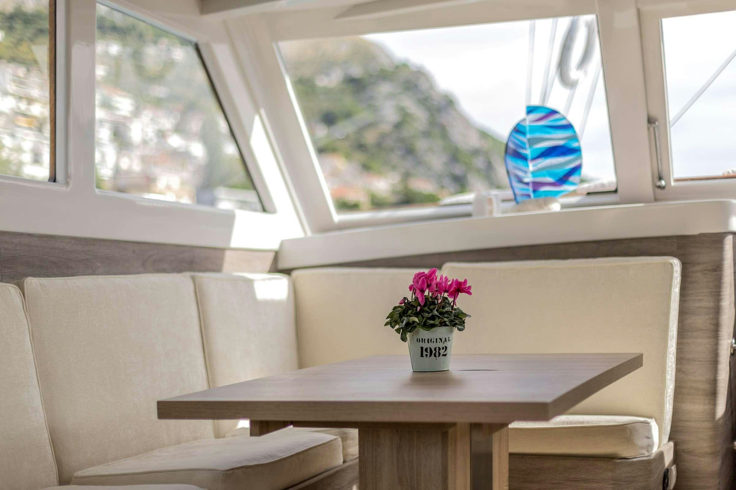 a room with a table and a vase with flowers in it aboard ANĐEO Yacht for Charter