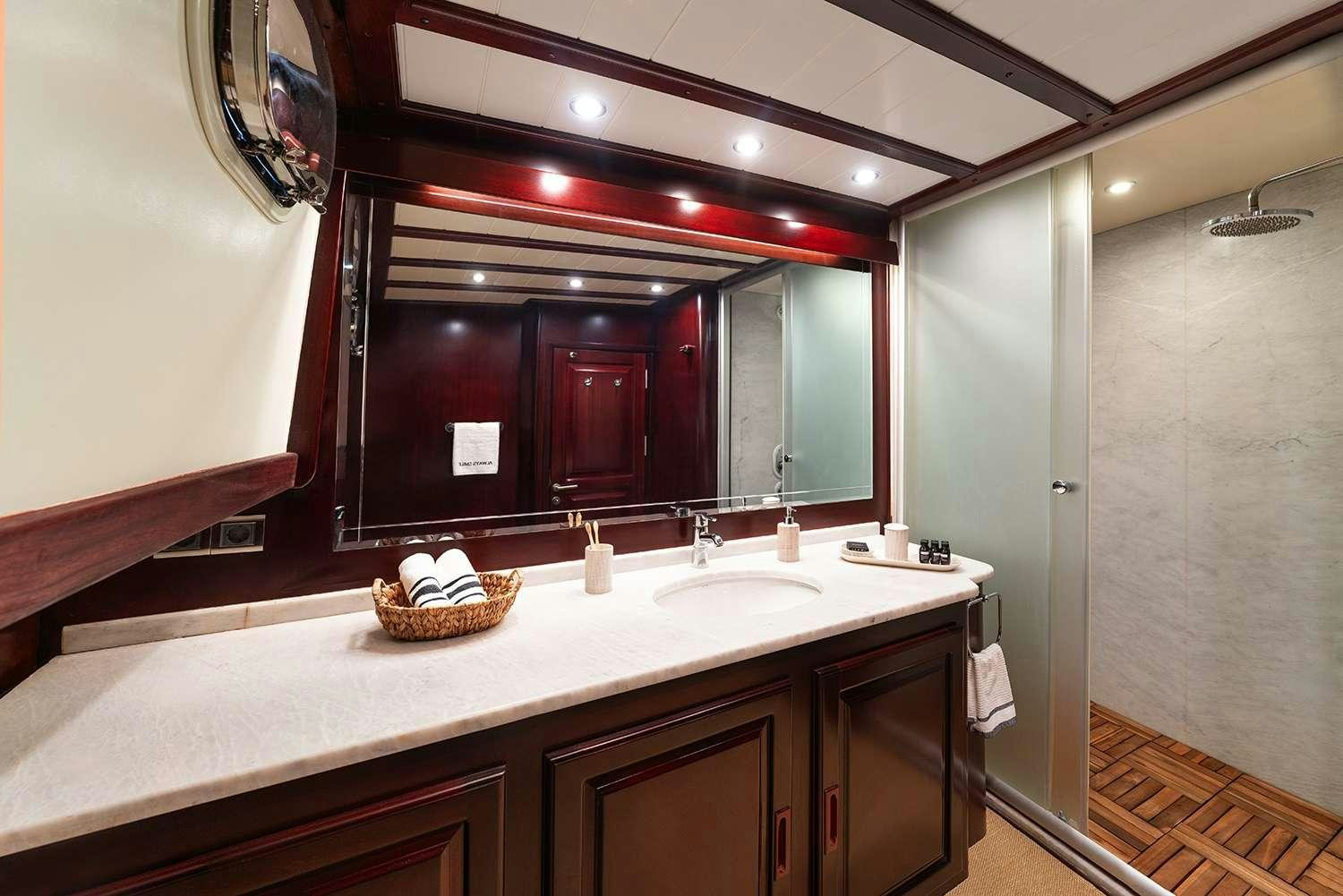 a bathroom with a countertop sink and a mirror aboard ALWAYS SMILE Yacht for Charter