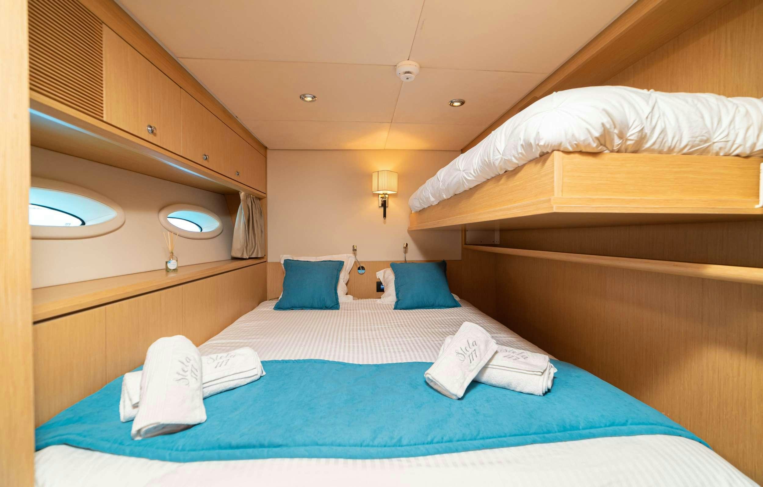 a bed with blue sheets aboard STELA 117 Yacht for Charter