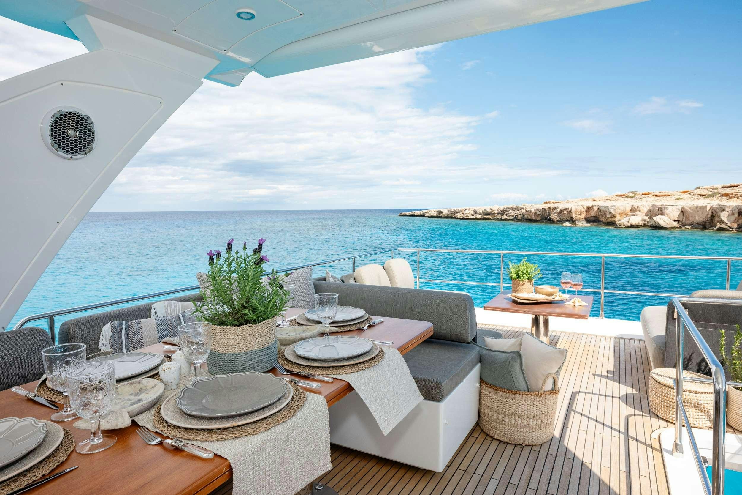 a table with plates and chairs on it next to a body of water aboard SEA YA Yacht for Charter
