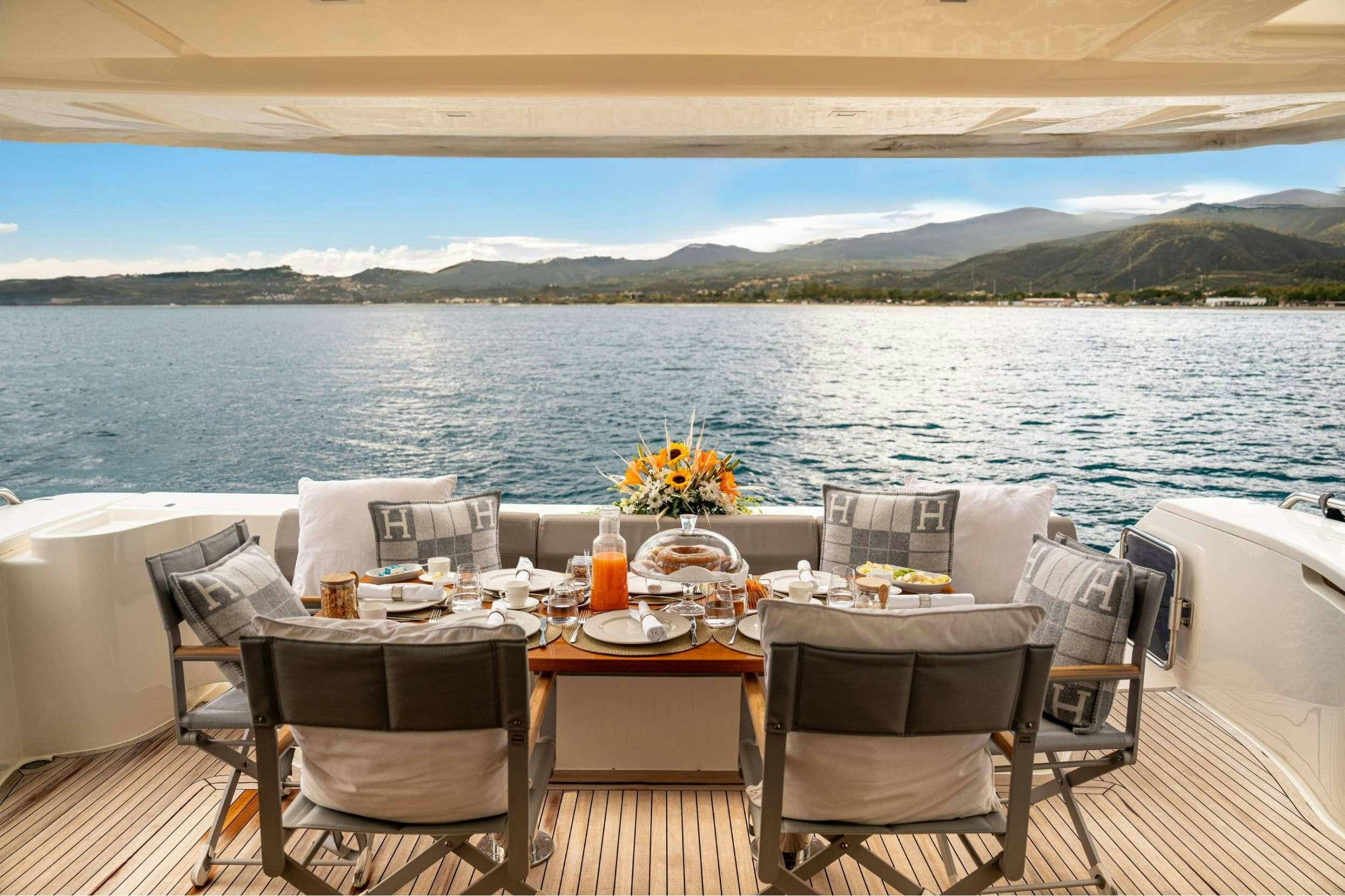 a table set for a meal on a deck overlooking a large body of water aboard SEA SONS Yacht for Charter