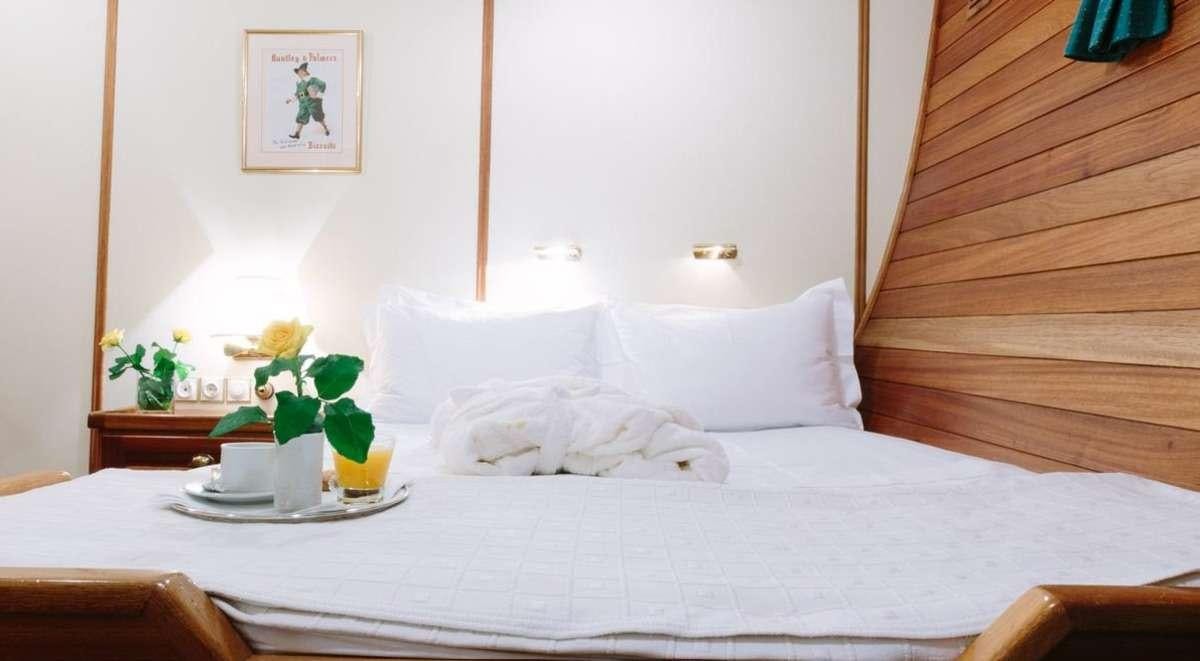 a bed with white sheets and pillows aboard SIR WINSTON CHURCHILL Yacht for Charter