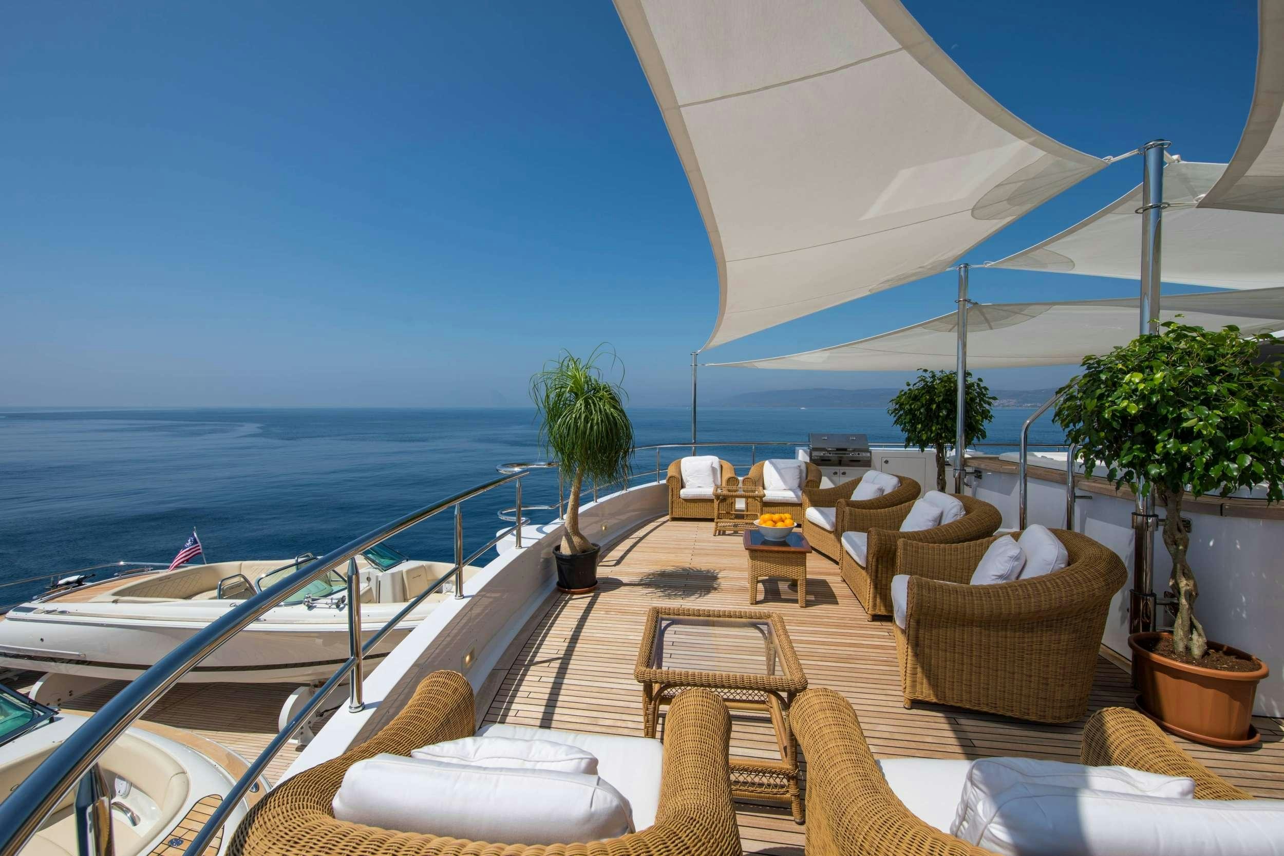 a deck with chairs and tables on it by the ocean aboard GRACE Yacht for Charter