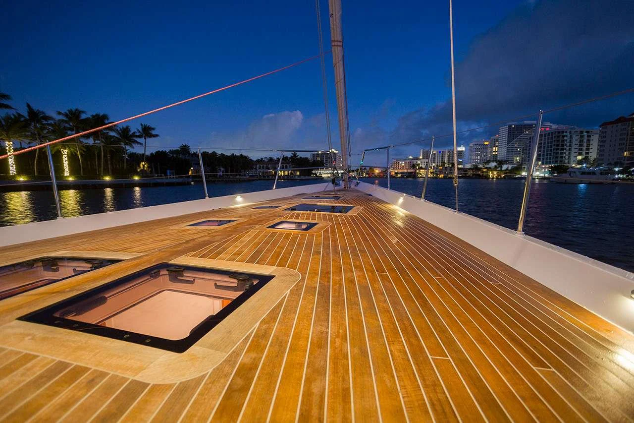 a large wooden deck with a railing and a city in the background aboard CIRRUS Yacht for Charter