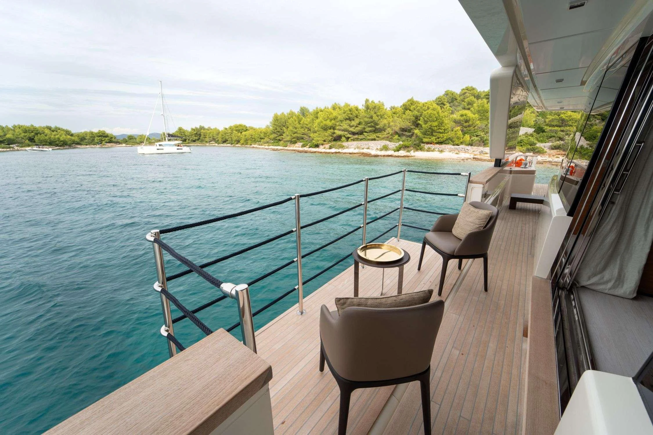 a deck with chairs and tables on it next to a body of water aboard SK Yacht for Charter