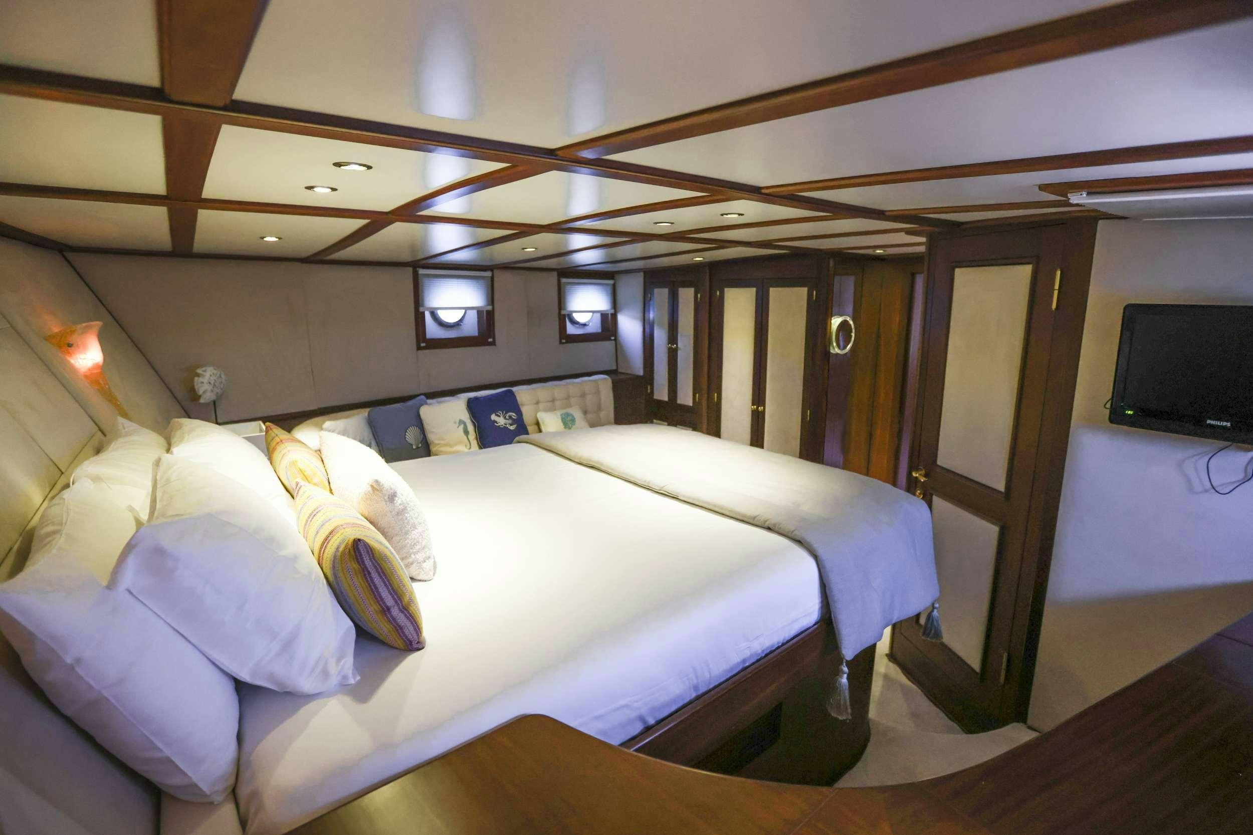 a room with a bed and a television aboard GAZELLA Yacht for Charter