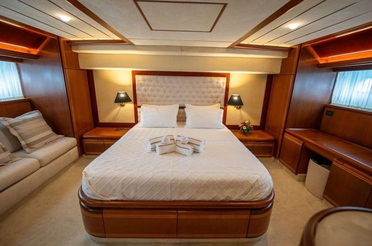 a bed with a white sheet and pillows in a room with a window aboard BELLAS BOY Yacht for Charter