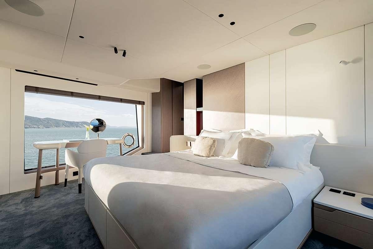a bed with a white sheet and a white table with a white table and chairs aboard ALADDIN SANE Yacht for Charter