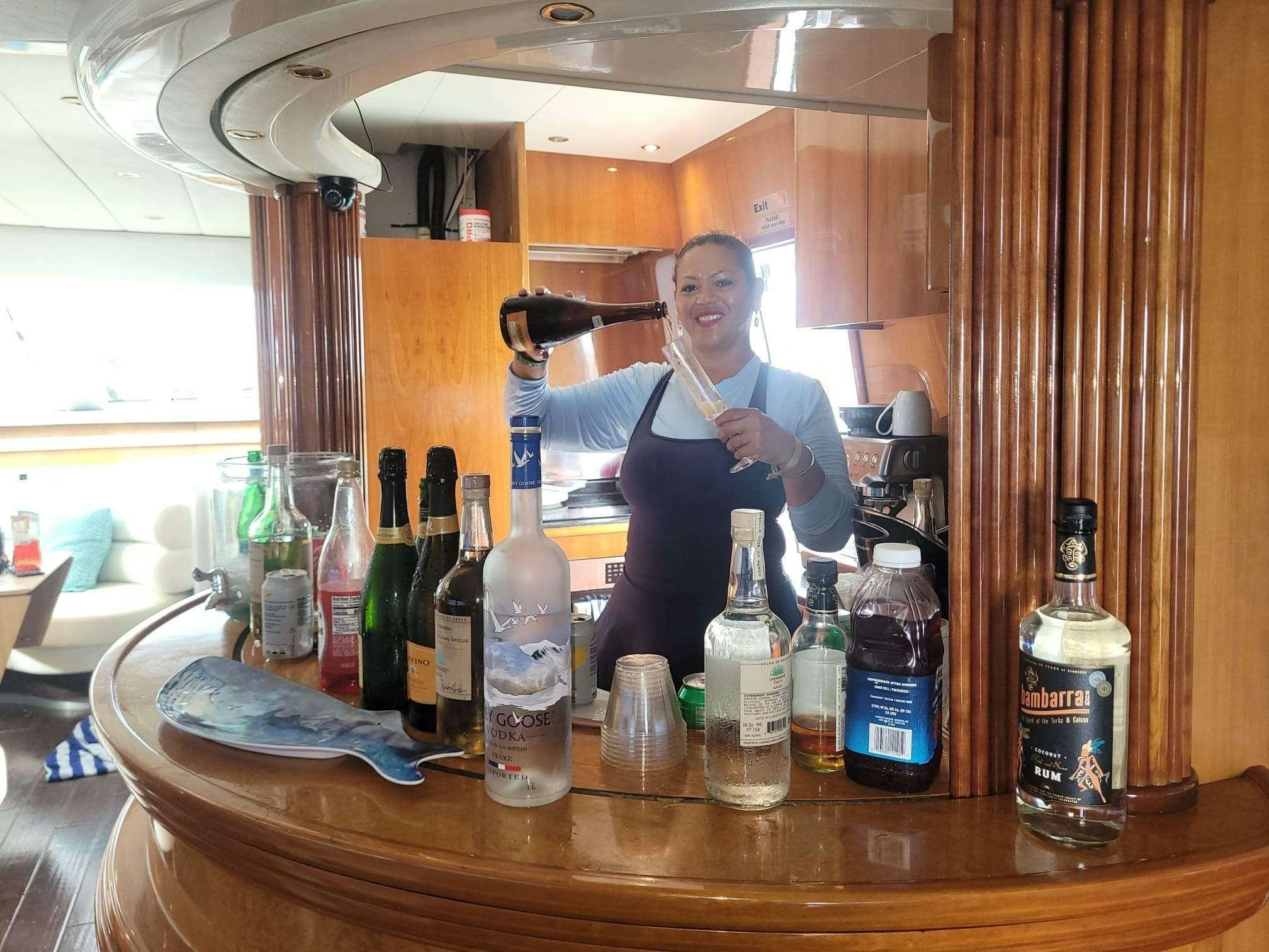 a person standing next to a table full of bottles aboard SAPHIRE BLUE Yacht for Charter