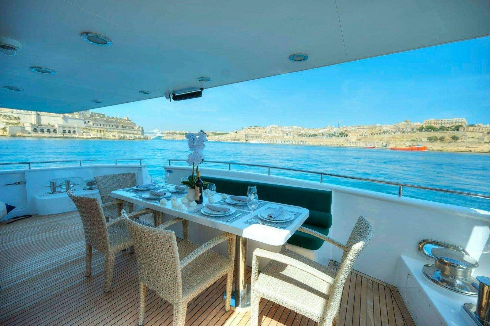 a table and chairs on a deck overlooking a large body of water aboard VOYAGER Yacht for Charter
