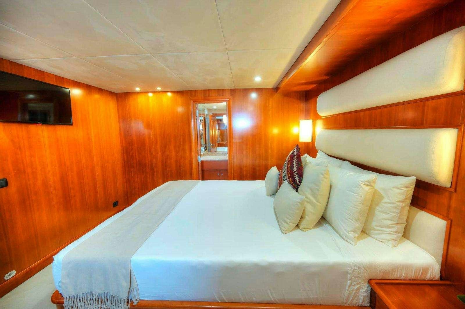 a room with a bed and a television aboard VOYAGER Yacht for Charter