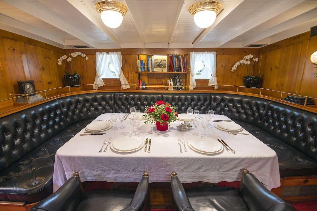 a large dining table with a vase of flowers on it aboard PURITAN Yacht for Charter