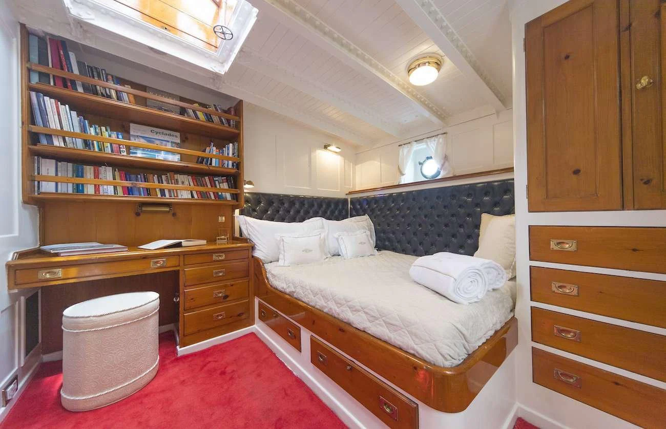 a bedroom with a bed and a bookcase aboard PURITAN Yacht for Charter