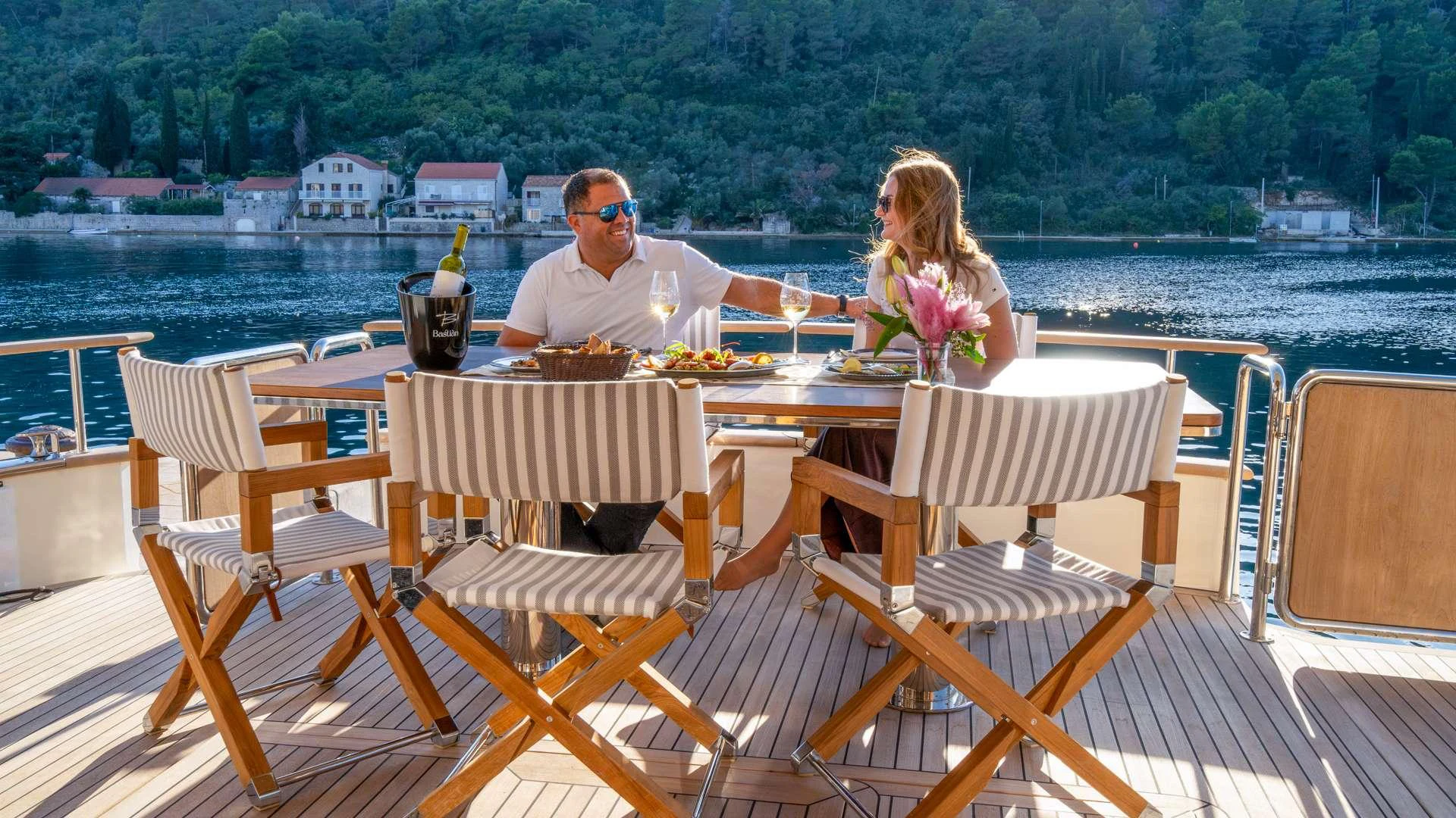 a man and woman sitting at a table with food and drinks on it aboard CLOUD 9 Yacht for Charter