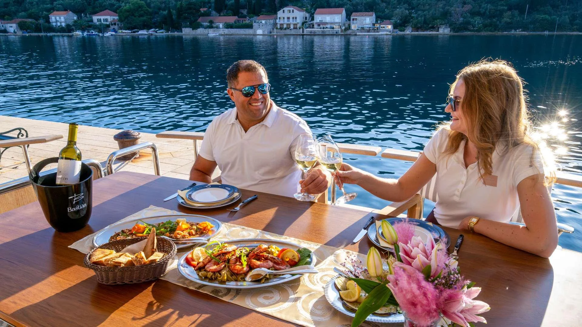 a man and woman sitting at a table with food and drinks on it aboard CLOUD 9 Yacht for Charter