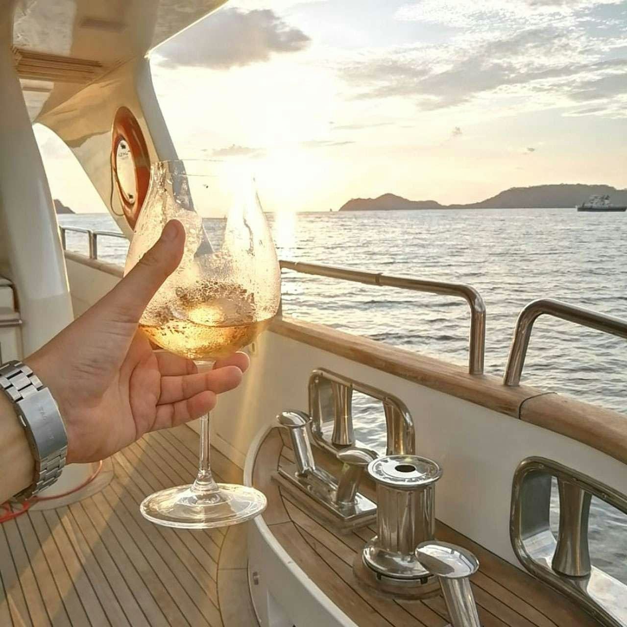a person holding a glass of wine aboard CAMY ED Yacht for Charter